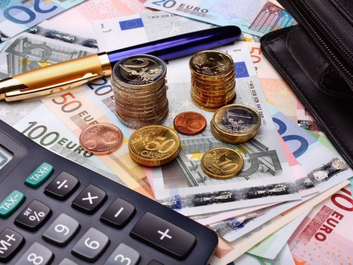 χαρτονομίσματα και κέρματα ευρώ αριθμομηχανή πάνω σε τραπέζι